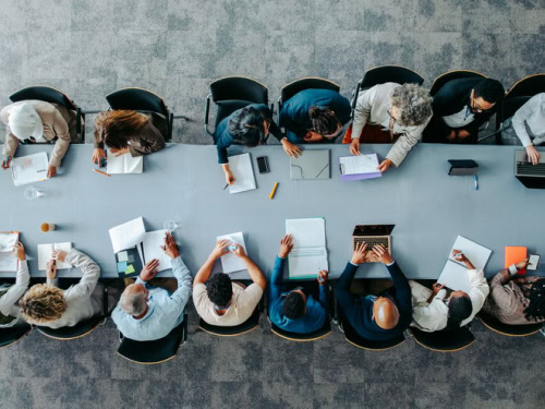Team sitzt an einem Konferenztisch und arbeitet gemeinsam an Unterlagen im Rahmen einer IT Strategieberatung